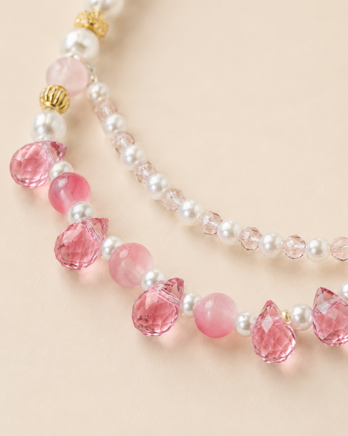 Close-up of faceted pink teardrop accents on pearl-style pet necklace