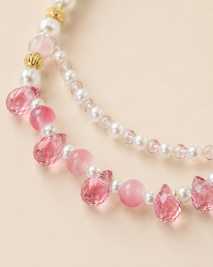 Close-up of faceted pink teardrop accents on pearl-style pet necklace