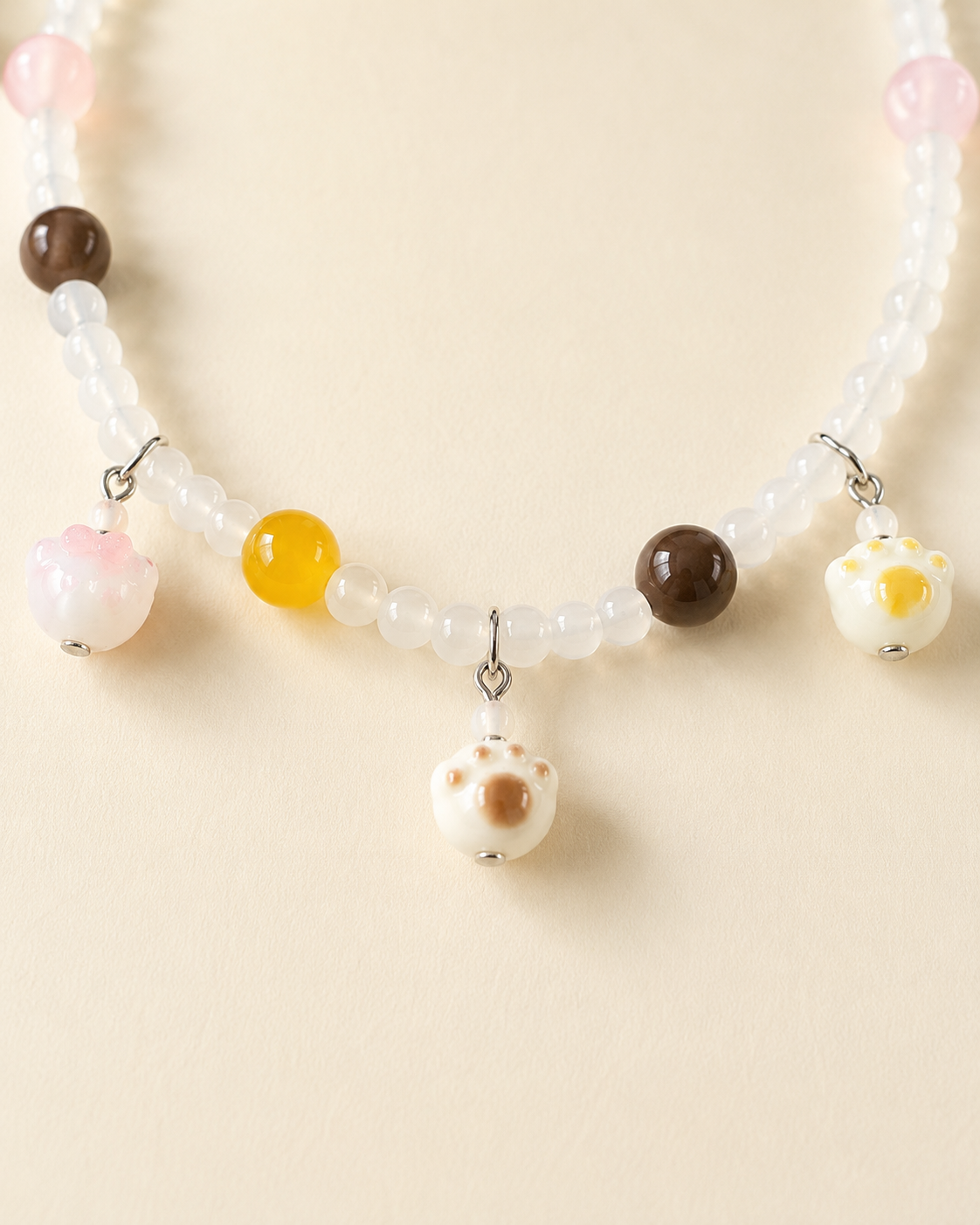 Close-up of dangling paw charms on beaded pet necklace