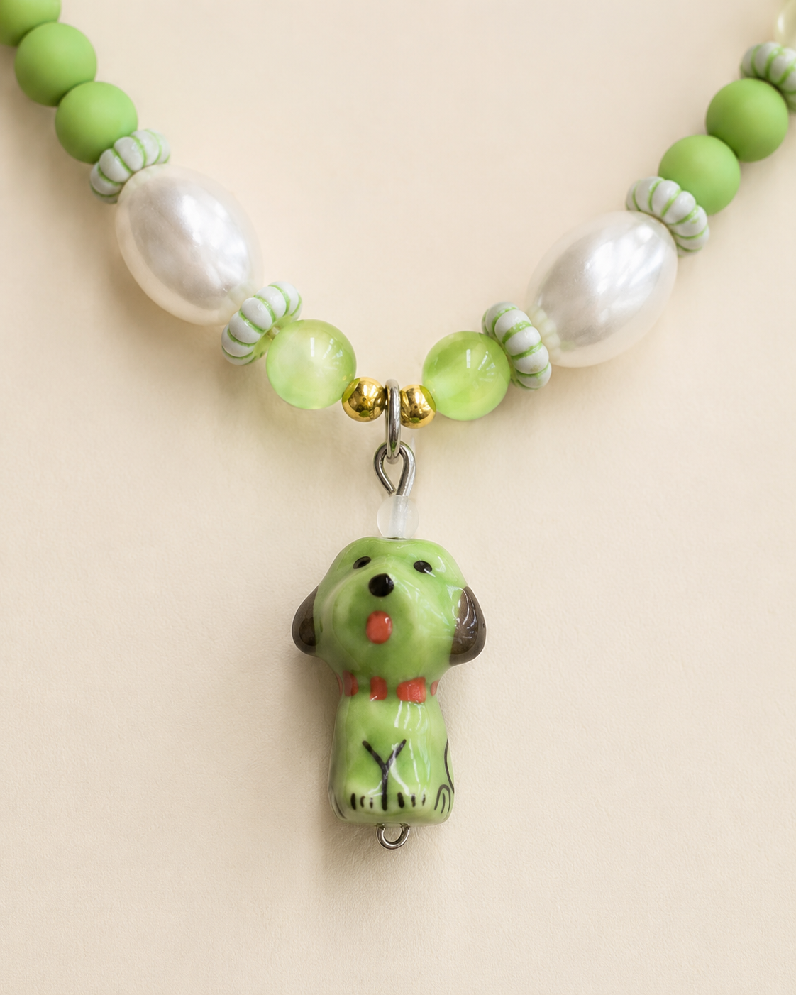 Close-up of green puppy charm and pearl-style beads on pet necklace