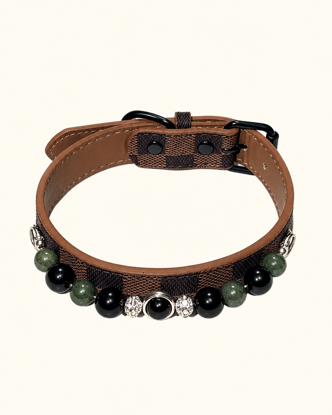 A brown and black plaid dog collar with tan leather trim, decorated with black and green beads and a central silver-toned crystal cluster, shown on a light cream background.