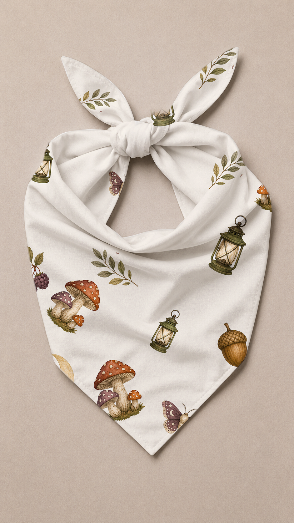 A white triangular bandana with a knotted bow, featuring an all-over print of mushrooms, lanterns, acorns, and leaves on a neutral beige background.