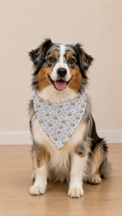 A tricolor Australian Shepherd dog wearing a white bandana with a delicate pink floral pattern, sitting on a light wood floor against a beige wall.