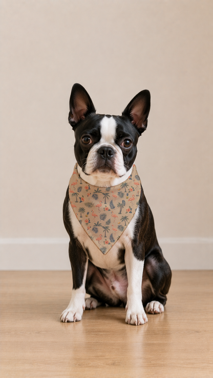 A Boston Terrier dog wearing a beige bandana with a small pink floral pattern, sitting on a light wood floor against a neutral beige background.