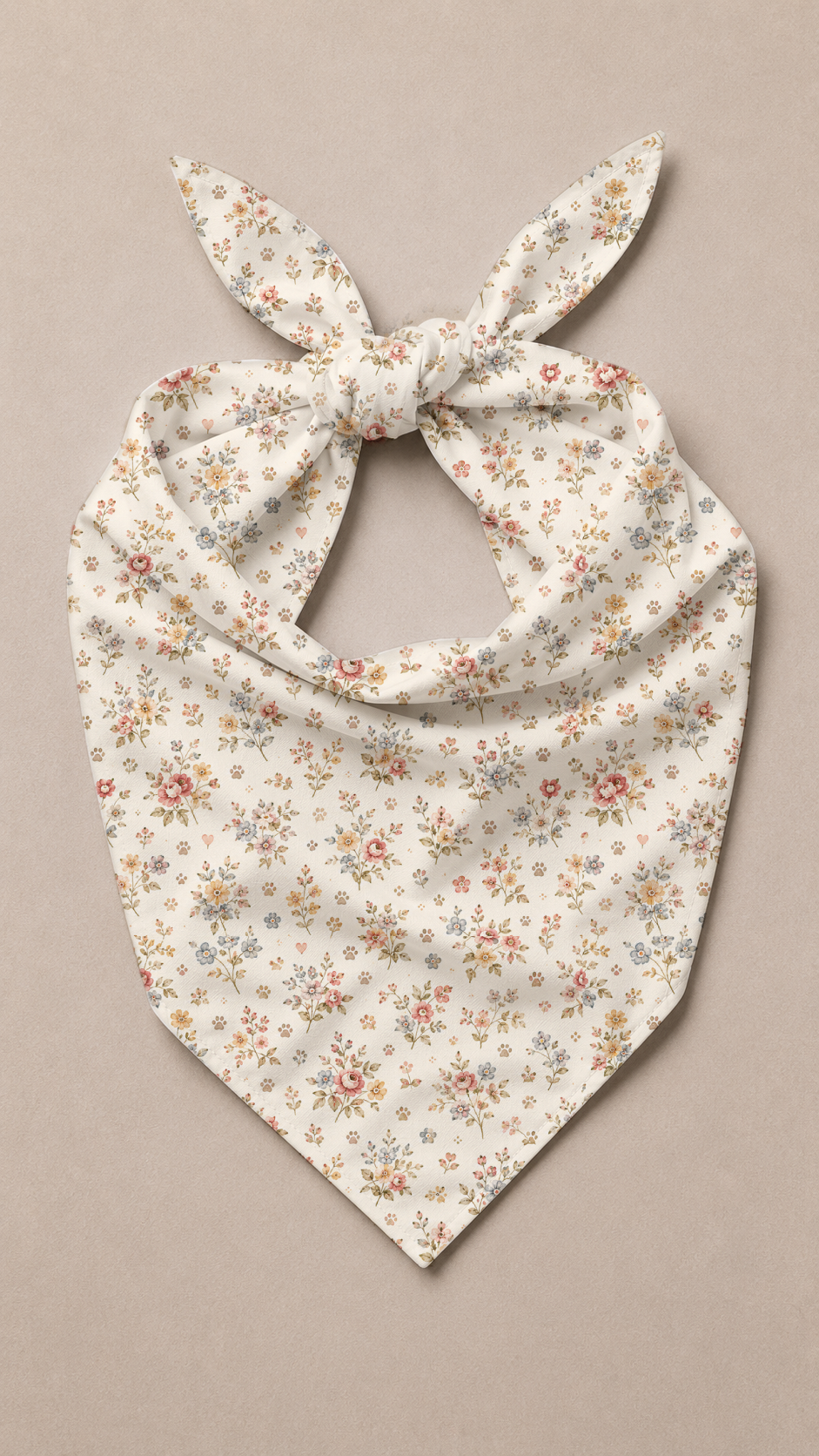 A cream-colored pet bandana with a delicate pink and orange floral print, tied in a bow at the top and styled flat on a neutral beige background.