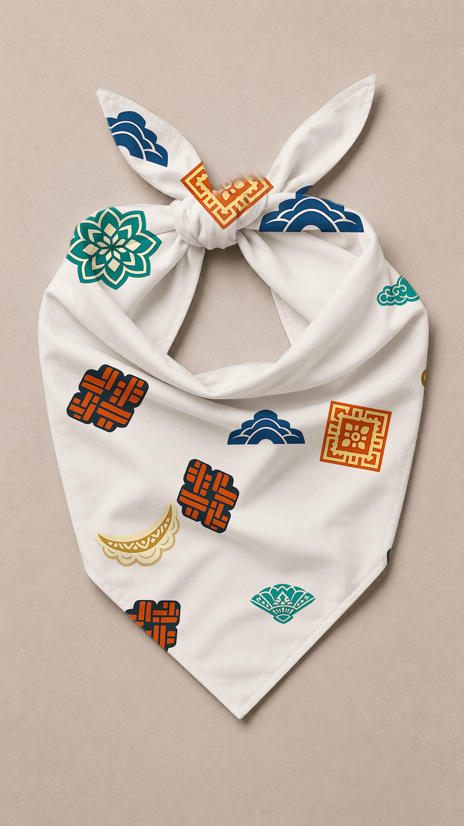 A white fabric bandana or scarf with a knot at the top, decorated with colorful traditional-style motifs including blue clouds, green lotus flowers, and orange geometric patterns, displayed flat against a neutral beige background.