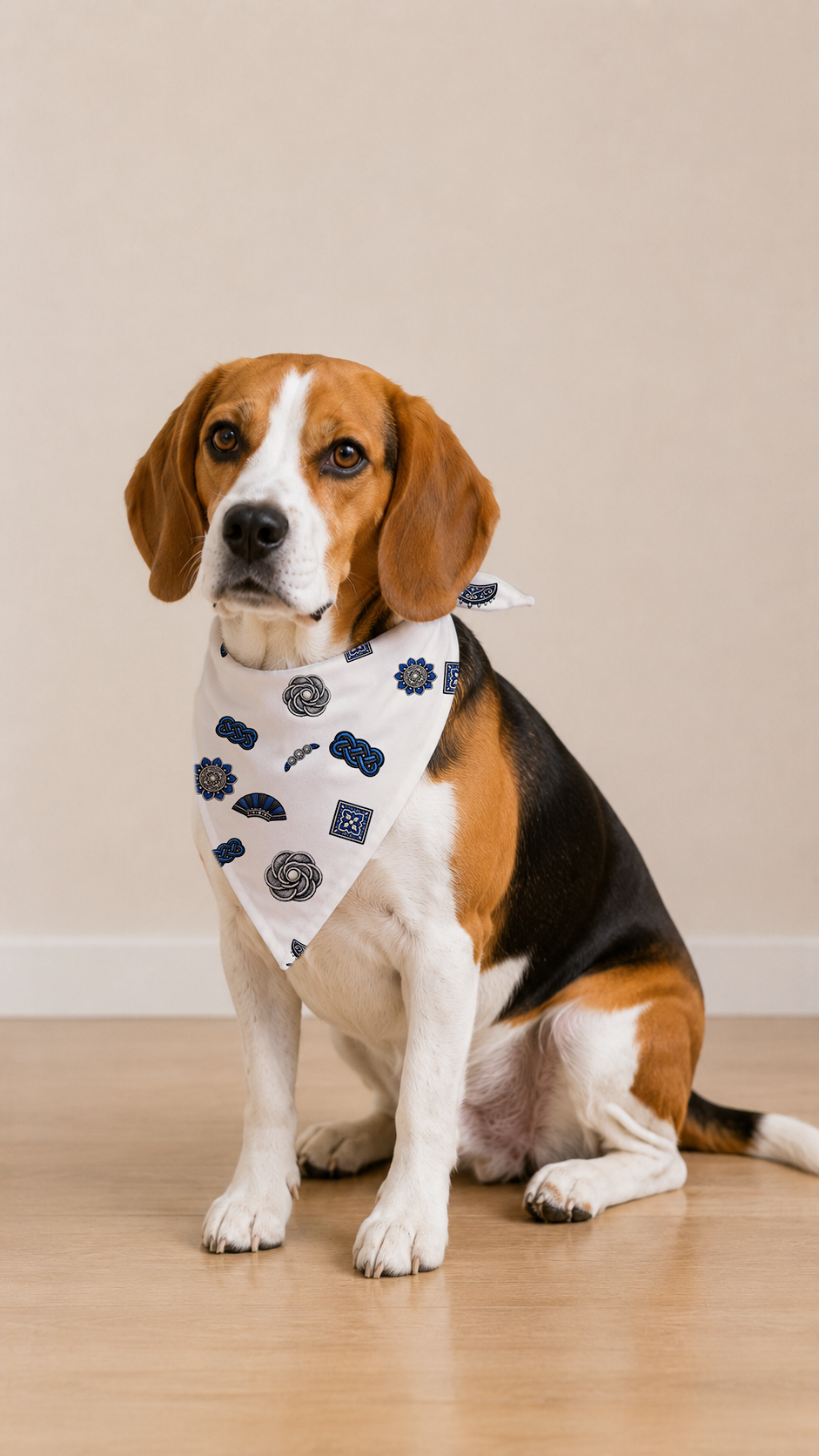 A beagle dog wearing a white bandana with a navy blue police badge pattern, sitting on a light wood floor against a beige wall.