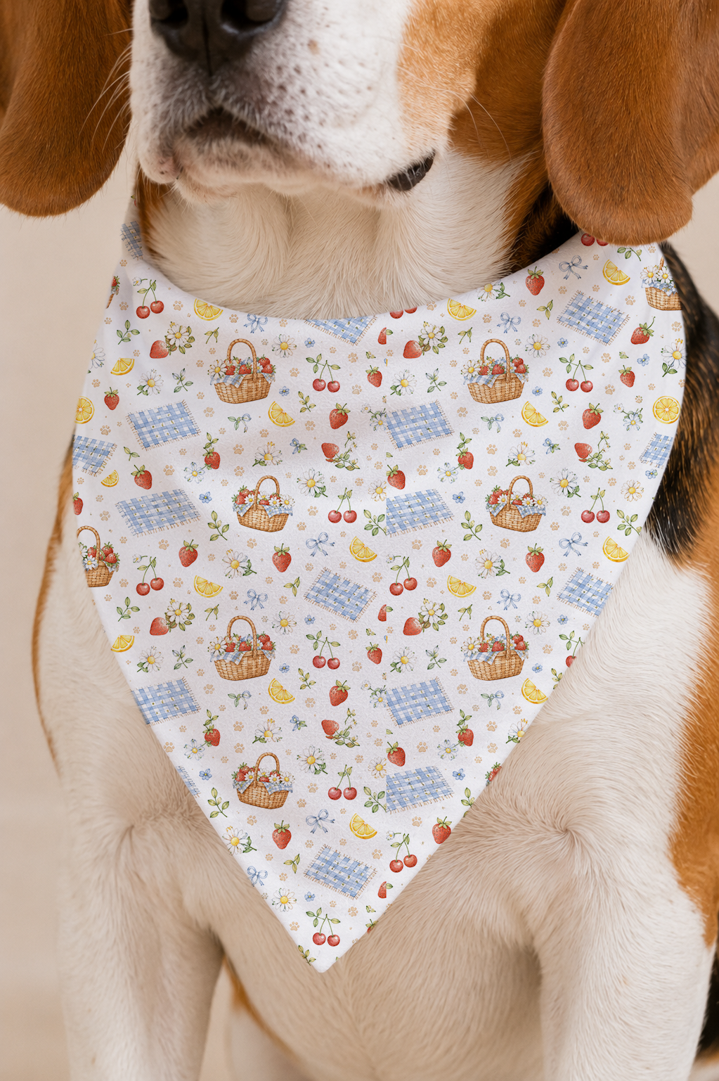 Closeup of a picnic dog bandana showing baskets, strawberries, cherries, daisies, and paw print details.