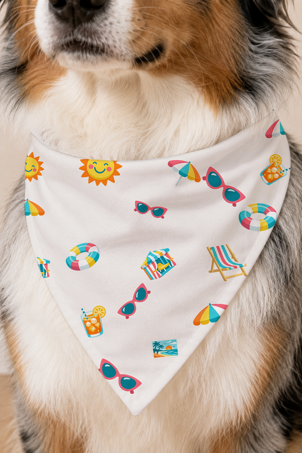 A close-up of a dog wearing a white triangular bandana with a colorful summer-themed print of sunglasses, beach umbrellas, a sun, a beach chair, and pool floats.