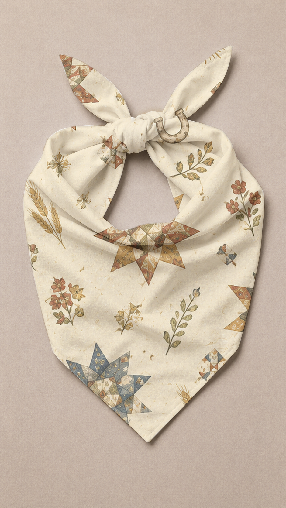 A cream-colored pet bandana with a tie knot, featuring a western-inspired print of brown stars, blue starbursts, and floral motifs, laid flat on a neutral beige background.