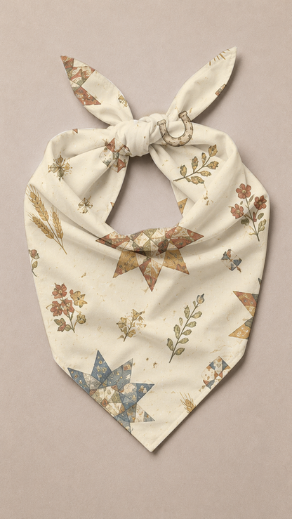 A cream-colored pet bandana with a tie knot, featuring a western-inspired print of brown stars, blue starbursts, and floral motifs, laid flat on a neutral beige background.