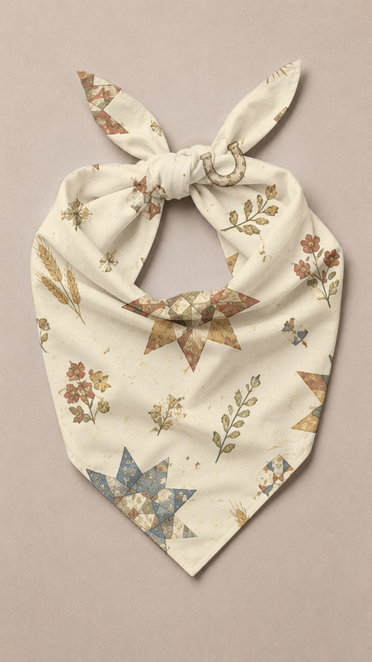 A cream-colored pet bandana with a tie knot, featuring a western-inspired print of brown stars, blue starbursts, and floral motifs, laid flat on a neutral beige background.
