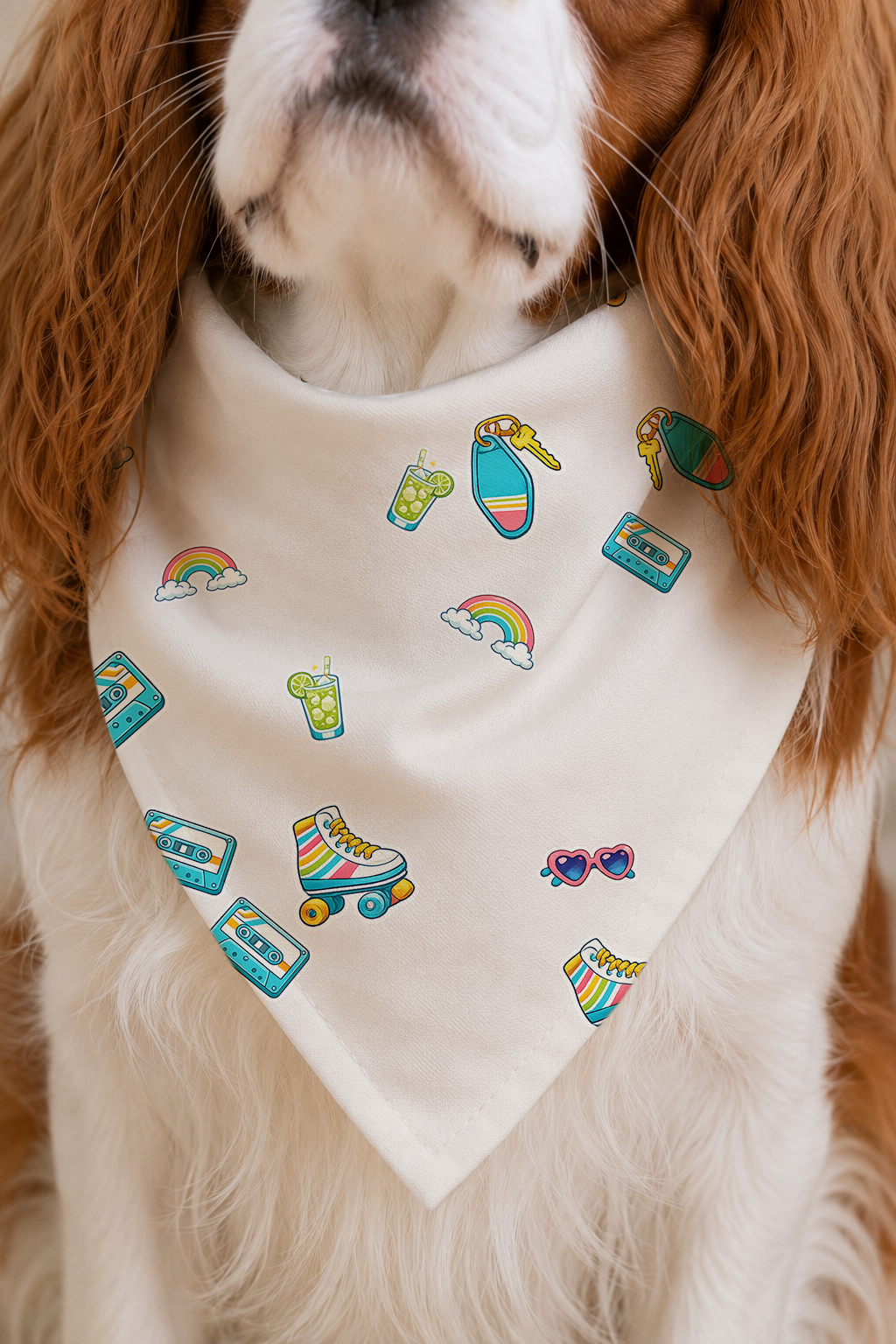 A close-up of a dog wearing a cream-colored bandana with colorful retro-themed prints including roller skates, cassettes, rainbows, and sunglasses.