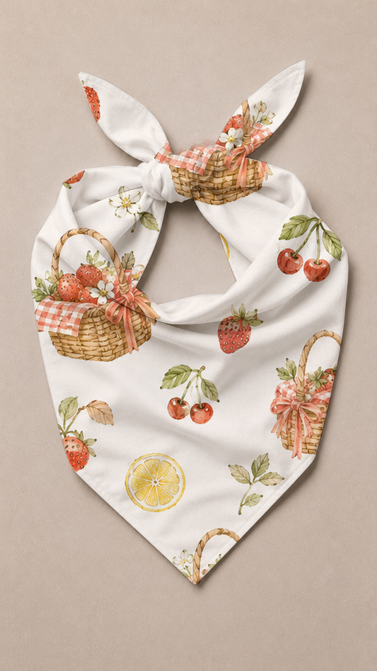 A white bandana-style pet scarf with a knotted top, featuring a vintage-style print of strawberry baskets, cherries, leaves, and a lemon slice on a neutral beige background.
