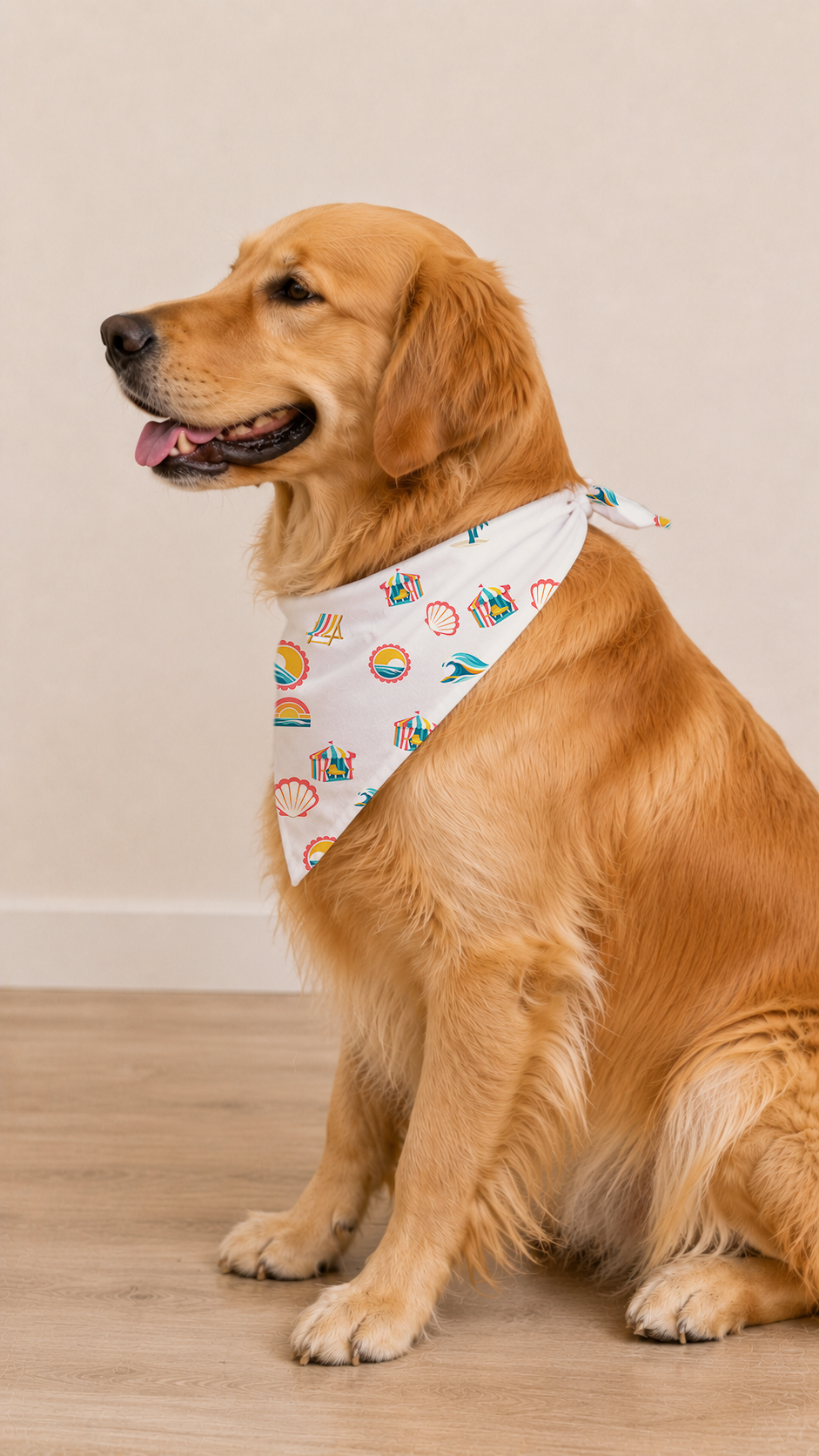 A golden retriever dog wearing a white bandana with a black, orange, and gray Halloween print, sitting on a light wood floor against a beige wall.