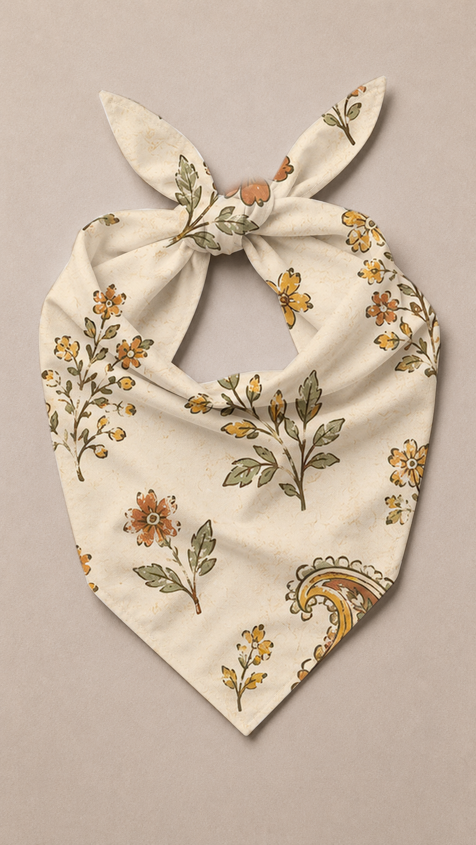 An off-white fabric bandana or pet scarf with a tie knot, featuring a vintage floral and paisley pattern in muted orange, yellow, and olive green on a solid taupe background.